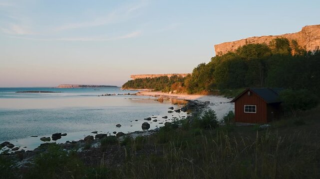Stora Karls&ouml; cliffs and coastline at sunset with Lilla Karls&ouml; island on the horizon, Gotland, Sweden