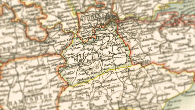 Macro close up of a vintage map highlighting Surrey shire in England, showcasing detailed cartography, major towns, and classic antique textures ideal for travel, geography, and historical themes.