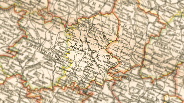 Macro close up of a vintage map highlighting Staffordshire in the United Kingdom, showcasing detailed cartography, major towns, and classic antique textures ideal for travel, geography, and historical