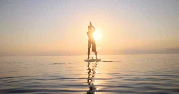 Young woman walking on sup board by the sea during summer vacation