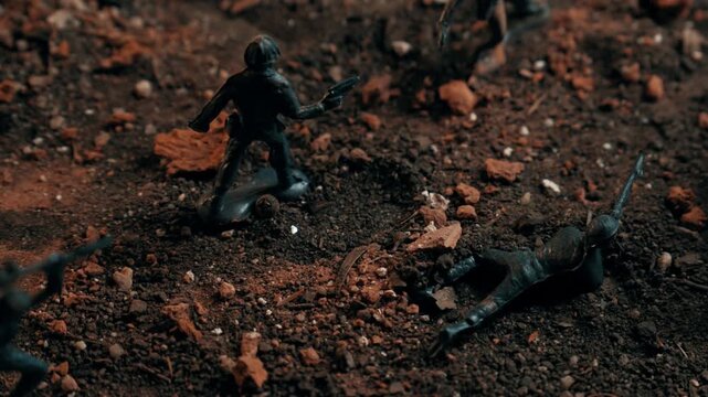 Plastic toy soldiers reenacting a combat scenario on a gritty battlefield. Fallen soldiers and troops in action create a dramatic war scene
