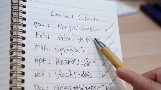 Close-up of a handwritten content calendar in a spiral notebook listing monthly campaigns including Ramadan, Black Friday, and Christmas, ideal for marketing and social media content.