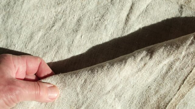 Hand with natural rough hemp fabric. Sunlight shadow. Rustic mood, eco-friendly, and sustainable living. Minimalism.