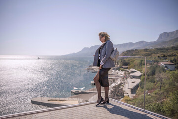 Fototapeta premium Businesswoman terrace sea view, stylish woman in blazer looks out over ocean panorama