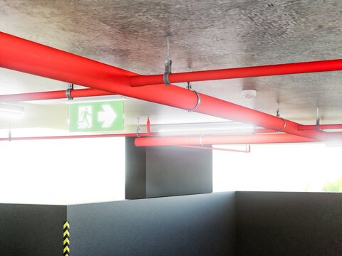 Green emergency exit sign with arrow pointing left, installed near red fire sprinkler pipes, 3D render.