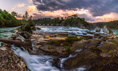 The Rhine Falls is the largest waterfall in Europe with railway viaduct at dusk, Schaffhausen, Switzerland. The falls are located on the High Rhine