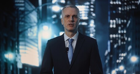 Fototapeta premium Professional Grey Haired Male Reporter In Dark Business Suit and Blue Tie Stands on City Street at Night, Speaking Into Microphone. Breaking News Concept, on Scene Reporting With Bokeh Lights.