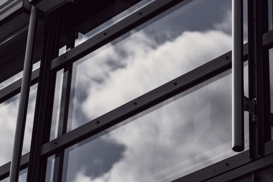 Modern glass window reflection of sky clouds within a facade frame showing architecture in an abstract minimalist composition for branding