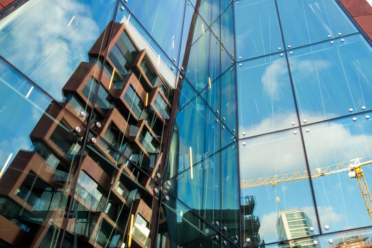 Modern urban construction behind a glass window reflection on a building facade showing architecture with crane lines and graphic geometry