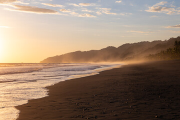The low sun's golden light illuminates the ocean spray on Carate Beach, with views of Corcovado NP at sunset. Costa Rica. © jiriviehmann
