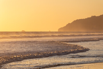The low sun's golden light illuminates the ocean spray on Carate Beach, with views of Corcovado NP at sunset. Costa Rica. © jiriviehmann