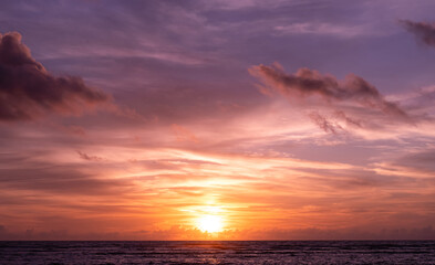 Fototapeta premium Colorful sunset over ocean horizon with dramatic clouds and glowing sky, tranquil seascape nature background, vibrant twilight light reflecting on water, peaceful travel and summer vacation concept