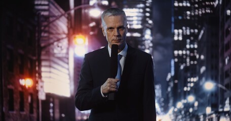Fototapeta premium Mature Male Reporter in Formal Wear Presenting News Story, Speaking Into Microphone While Looking at Camera. Concept of Broadcast Journalism, on Location Reporting Amidst Vibrant Urban Night.