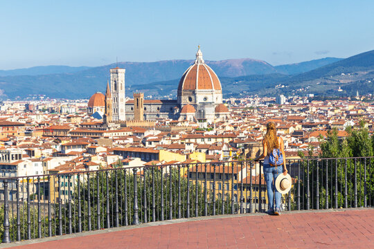 Woman tourist admiring Florence skyline with Duomo and Giotto's Bell Tower from Piazzale Michelangelo, Italy