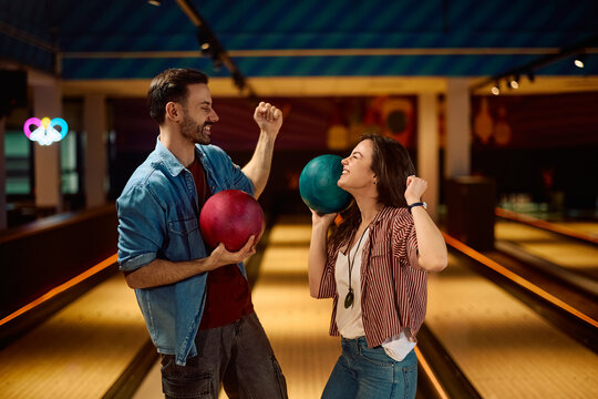 Cheerful couple celebrating while playing ten pin bowling at club.