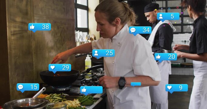 Vertical video: Adding carrots, lead chef in white coat stirring wok at stove, drawing social likes