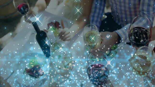 Diners prompted by shared meal reaching for glasses toasting at table, sparkle overlay on glasses