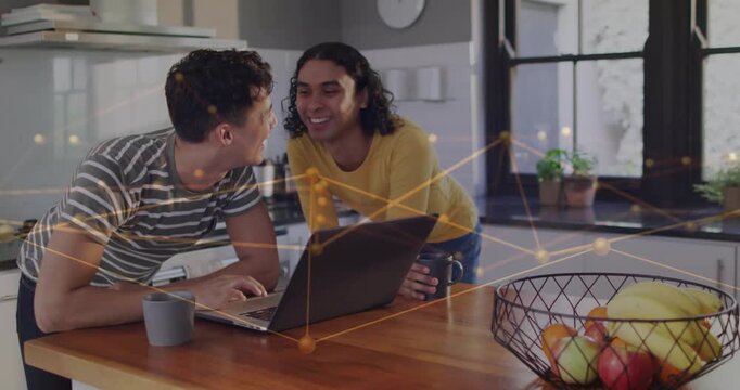 Male adult typing after quick glance at laptop, non-binary adult leaning, sharing remote work tasks