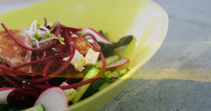 Vertical video: Camera moving closer, revealing lime-green bowl salad textures for food photography