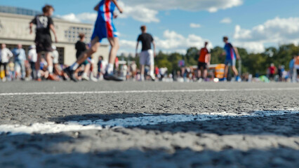 Obraz premium Low angle view of an asphalt race track with blurred marathon runners in the background on a sunny day.
