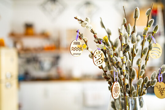 On the kitchen table wooden Easter eggs are placed on the branches of a flowering willow.