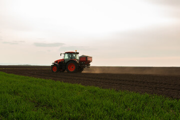 Fototapeta premium Tractor spreading artificial fertilizers in field