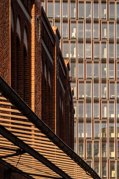 Industrial architectural detail of red brick building with steel structure and stairs creating dramatic shadows and repeating pattern across the facade surface