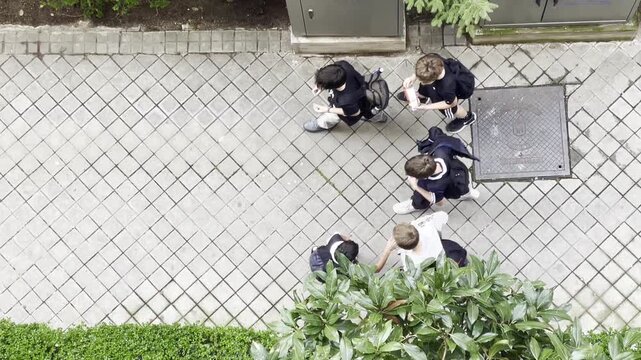 Grupo de ni&ntilde;os escolares y amigos del colegio en pandilla con mochilas de clase en perspectiva a&eacute;rea