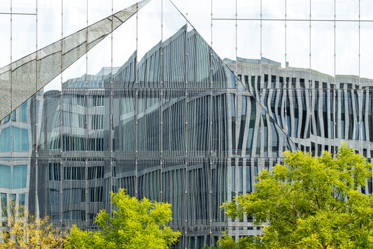 Contemporary skyline view with modern glass architecture building facade in an urban setting with trees and greenery in clear daylight