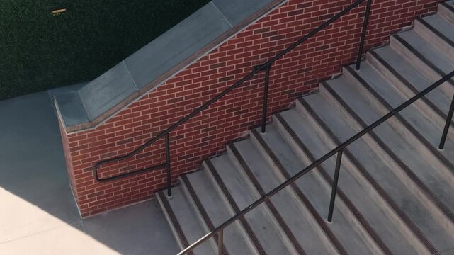 Slow steady pan of concrete stairs and brick wall with black metal railings