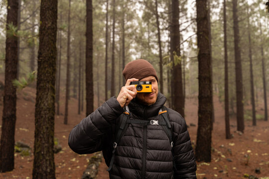 Photographer hiking with camera in pine forest at Chinyero Tenerife