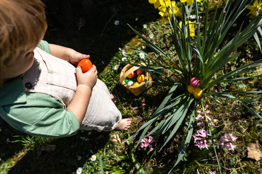 Child searching for Easter eggs in garden during spring egg hunt