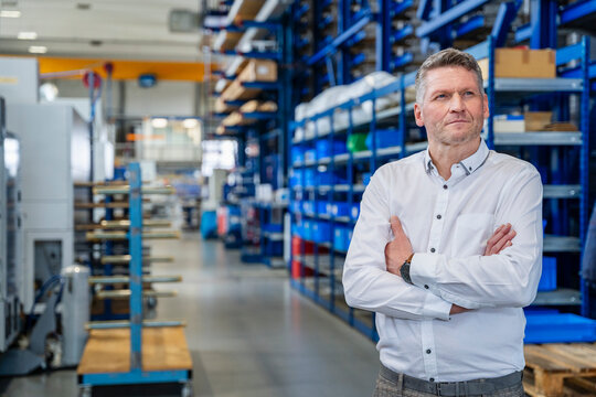 Confident manager standing in modern production hall interior