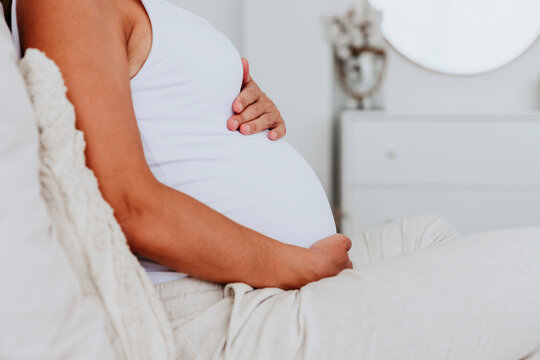 Pregnant woman relaxing at home with hand on belly