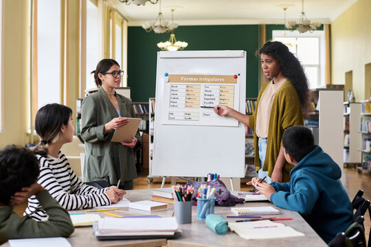 Students and teacher in a language class discussing in a library setting