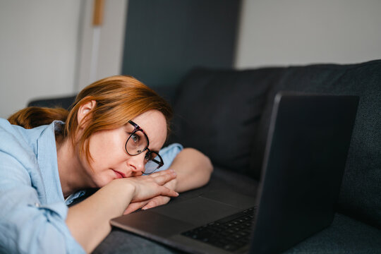 Woman with burnout and mental overload at home with laptop on sofa