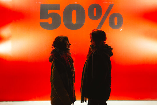Silhouettes in front of sale advertisement in urban shopping scene