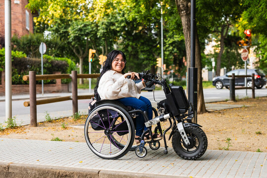Woman using electric handbike wheelchair outdoors in an urban setting