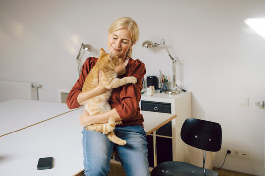 Woman holding a cat in a modern office setting