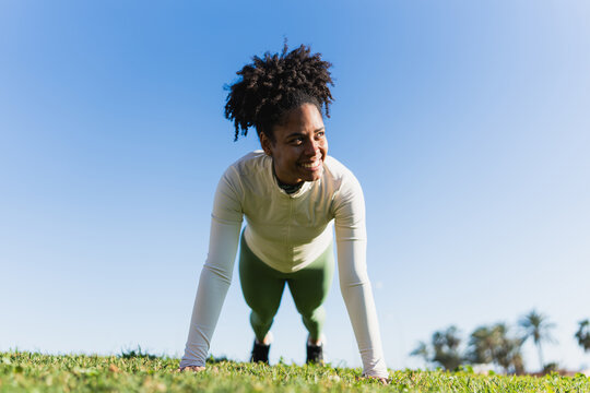Athlete doing push up outdoors on grass in sunny morning