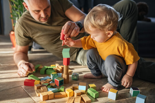 Father and child building with wooden blocks during indoor playtime