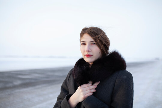 Woman in winter coat standing on snowy highway during blizzard