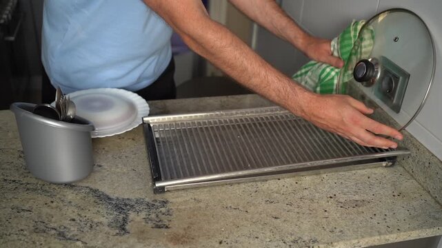 Caucasian man's hands drying dishes on a granite countertop after washing them in the kitchen
