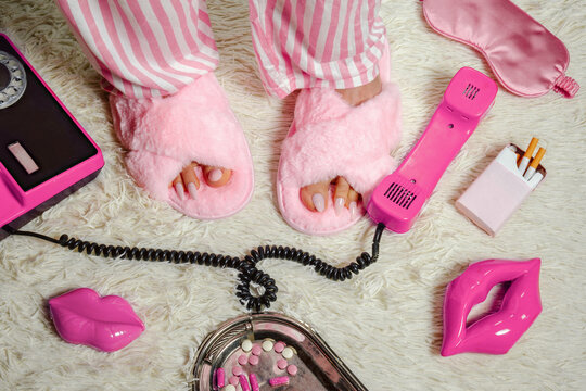 Pink fluffy slippers with telephone and cigarettes on hotel carpet