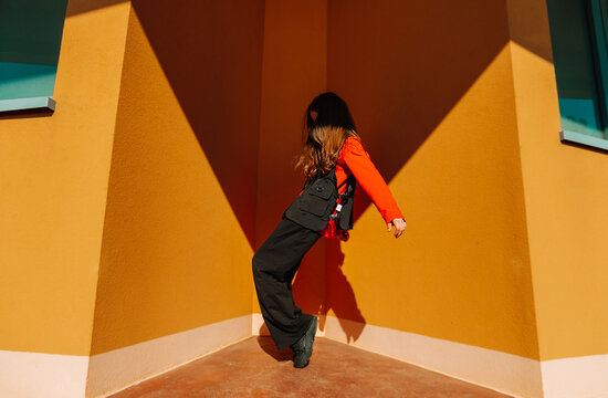 Teenager dancing energetically in sunlight casting dramatic shadow