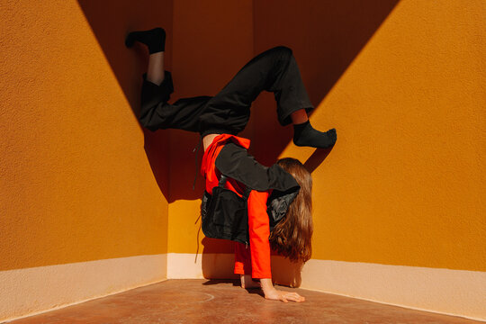 Dancer in handstand pose on public ground with dramatic shadow and light