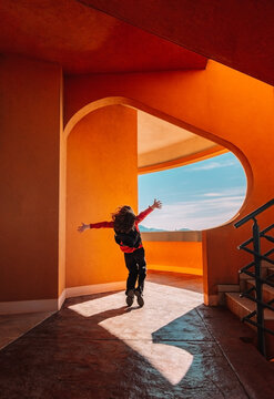Teenager dancing energetically in modern terracotta architecture