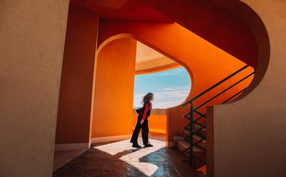 Teenager walking energetically by terracotta architecture in daylight