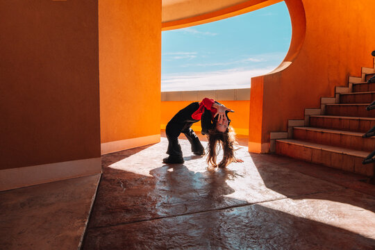 Teenager dancing on public ground against terracotta architecture