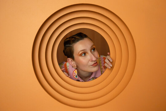 Creative portrait of a stylish person with earrings in orange setting